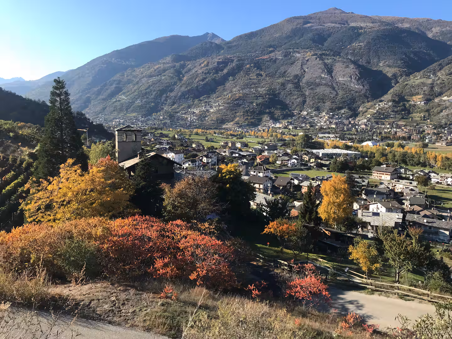 Panoramic autumn valley view with mountain backdrop and colourful foliage